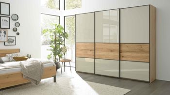 Kleiderschrank Interliving aus Holz in Hellgrau Interliving Schlafzimmer Serie 1027 – Schwebetürenschrank Champagner & Eiche bianco - drei Türen, Breite ca. 250 cm